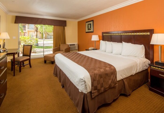 Days Inn by Wyndham Palm Springs: Room interior with king bed, desk, chair, and view to the outside. Gay-friendly hotel in Palm Springs.