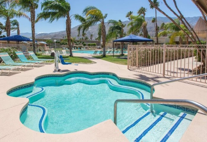 Days Inn by Wyndham Palm Springs gay-friendly hotel pool. Palm trees, lounge chairs, and mountain views. Perfect for gay men travel.