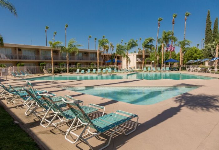 Days Inn by Wyndham Palm Springs pool view. Gay-friendly hotel with palm trees, lounge chairs, and a refreshing pool. Perfect for LGBT travelers.