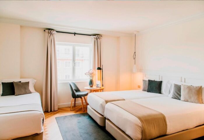 Dear Hotel Madrid room with twin beds and a single bed. Gay-friendly hotel with modern decor and natural light. Comfortable stay in Madrid.