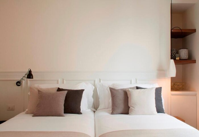 Dear Hotel Madrid room. Gay-friendly hotel with twin beds, white linens, and stylish pillows. Modern design with shelves. Perfect for gay travel.