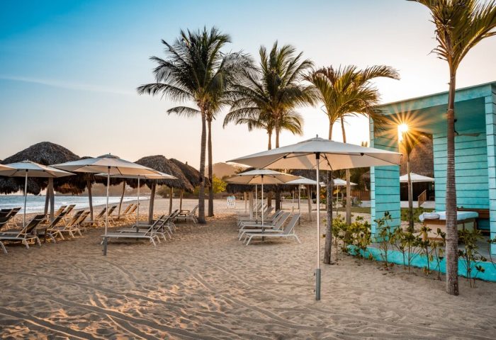 Gay-friendly Delta Hotels by Marriott Riviera Nayarit All-Inclusive beach. Loungers, umbrellas, and palm trees at a gay resort.
