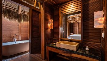 Bathroom at Gay-Friendly Delta Hotels by Marriott Riviera Nayarit All-Inclusive. Wood accents, stone sink, bathtub, and view into bedroom.
