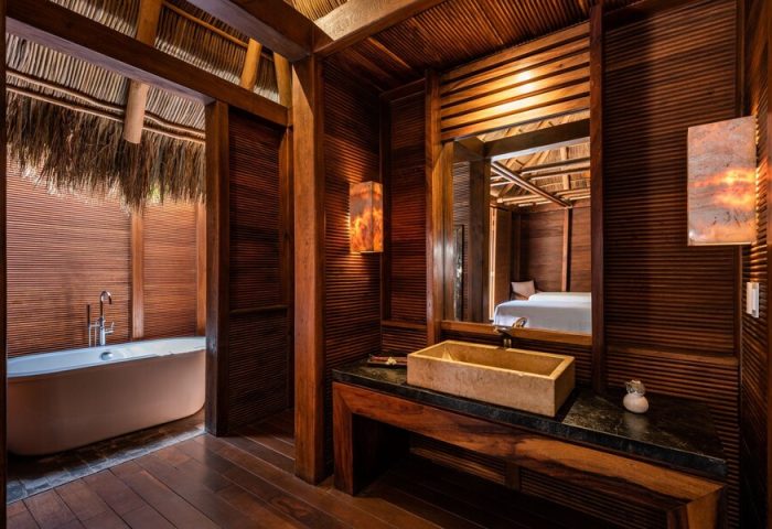 Bathroom at Gay-Friendly Delta Hotels by Marriott Riviera Nayarit All-Inclusive. Wood accents, stone sink, bathtub, and view into bedroom.