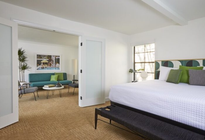 Descanso Resort gay-friendly hotel room. Bedroom with a king-size bed, bench, and living room in a Palm Springs men's resort.