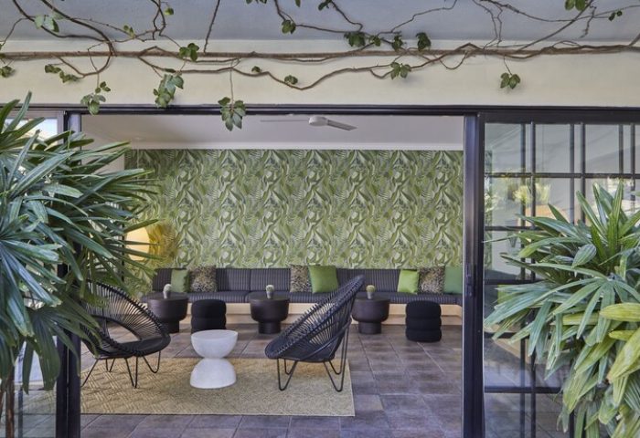 Descanso Resort, a gay-friendly men's resort. Stylish lounge area with tropical wallpaper, seating. Relaxing vacation vibes.