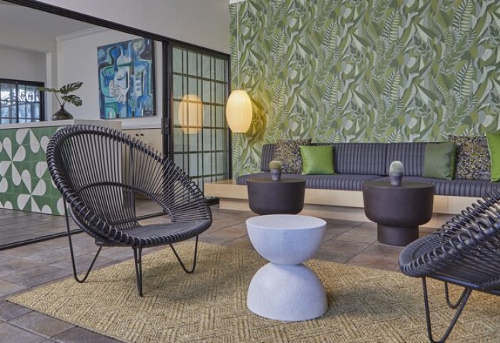 Descanso Resort, a men's gay-friendly resort. Stylish lounge area with chairs, sofa, and tropical wallpaper. Relax at this Palm Springs hotel.