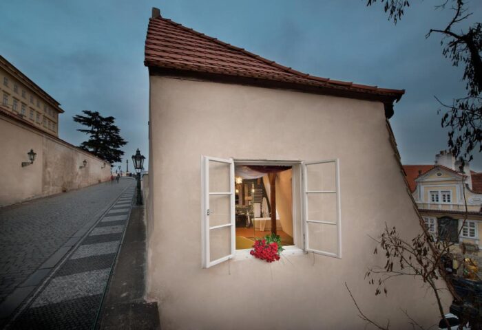 Design Hotel Neruda, a gay-friendly hotel. Exterior view of a room with an open window, red flowers, and a glimpse of the interior.