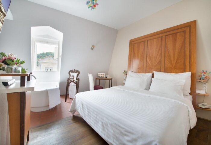 Gay-Friendly Design Hotel Neruda room. Bedroom with a large bed and a bathtub by the window. Gay travel advice for design hotels.