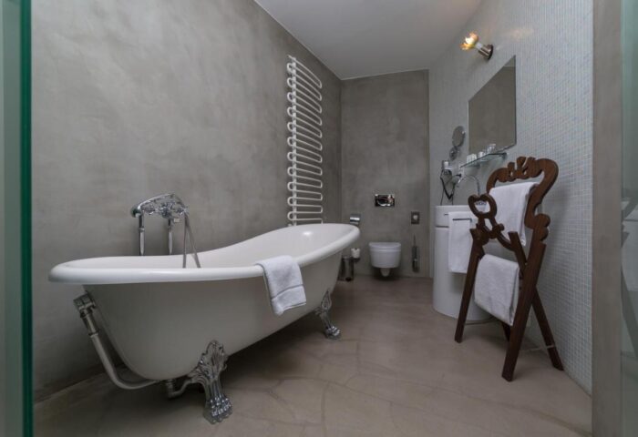 Bathroom at Design Hotel Neruda, a gay-friendly hotel. Features a clawfoot tub, towel rack, modern fixtures, and stylish design elements.