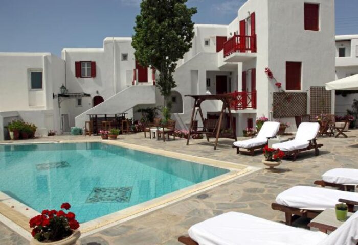 Despotiko Hotel, a gay-friendly hotel. Swimming pool with sun loungers in a whitewashed building with red accents. Ideal for gay men travel.