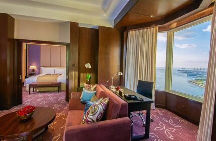 Diamond Hotel gay-friendly suite. Living area with sofa, desk, and ocean view. Bedroom visible through doorway. Luxury gay travel.