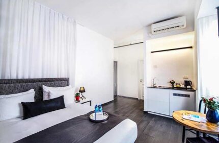 Gay-friendly Dizengoff Avenue Boutique Hotel room. Modern design, kitchenette, bed with pillows, and table. Great for gay travel in Tel Aviv.