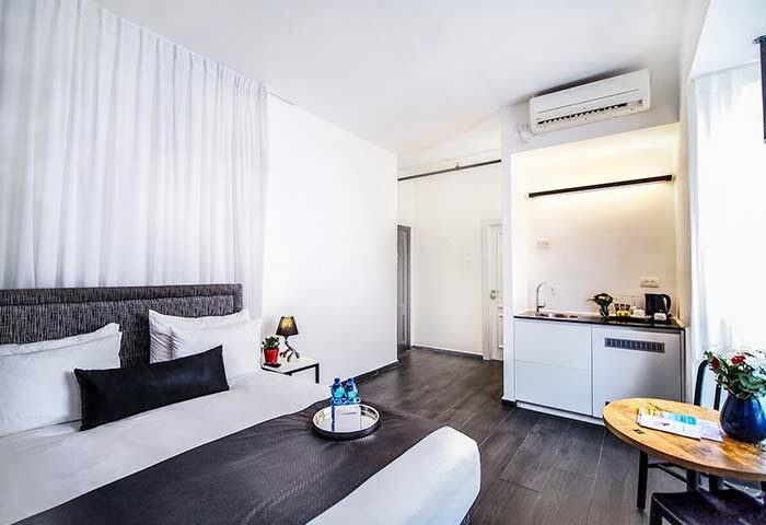 Gay-friendly Dizengoff Avenue Boutique Hotel room. Modern design, kitchenette, bed with pillows, and table. Great for gay travel in Tel Aviv.