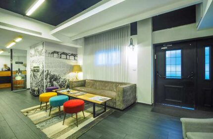 Dizengoff Avenue Boutique Hotel's lobby. Gay-friendly hotel interior with colorful stools, sofa, and beach-themed wall art. A stylish Tel Aviv stay.