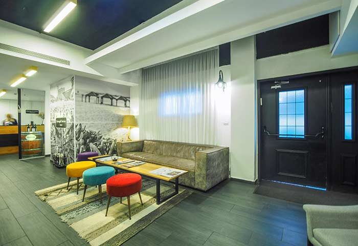 Dizengoff Avenue Boutique Hotel's lobby. Gay-friendly hotel interior with colorful stools, sofa, and beach-themed wall art. A stylish Tel Aviv stay.