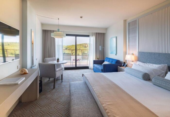 Dolce by Wyndham Sitges gay-friendly hotel room. Balcony view, sofa, and bed. Upscale gay travel accommodations in Sitges, Spain.