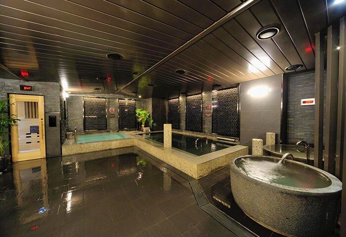 Dormy Inn Premium Seoul Garosugil gay-friendly hotel onsen. Features multiple hot tubs, sauna, and sleek, modern design. Relaxing spa experience.