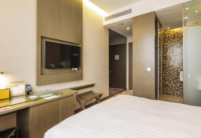 Dorsett Singapore gay-friendly hotel room. Clean, modern design with a TV, desk, and a partially visible shower with mosaic tiles. Comfortable stay for gay travelers.