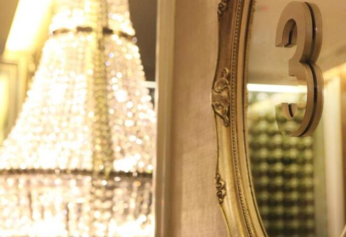 Dorsett Singapore gay-friendly hotel detail: A decorative mirror with the number 3 on the wall. A chandelier is visible in the background.