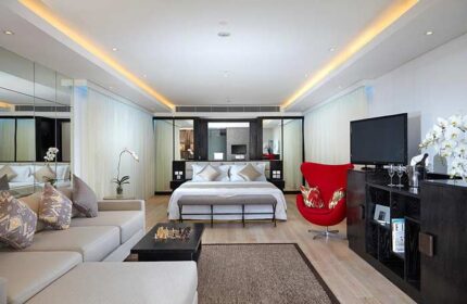 Double-Six Luxury Hotel Seminyak suite. Gay-friendly hotel room with bed, couch, and red chair. Upscale Bali travel for gay men.