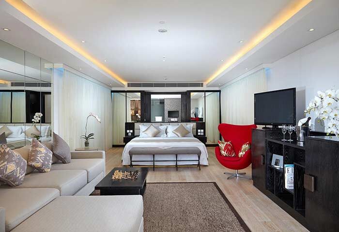 Double-Six Luxury Hotel Seminyak suite. Gay-friendly hotel room with bed, couch, and red chair. Upscale Bali travel for gay men.