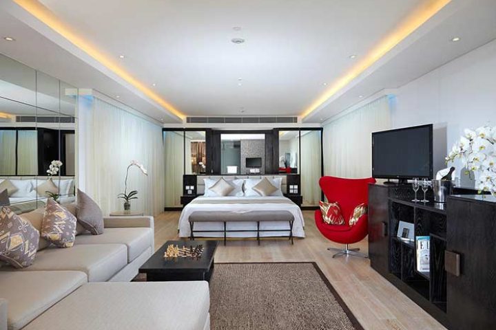 Double-Six Luxury Hotel Seminyak suite. Gay-friendly hotel room with bed, couch, and red chair. Upscale Bali travel for gay men.