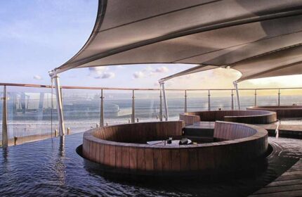 Double-Six Luxury Hotel Seminyak's gay-friendly rooftop bar. Wooden seating areas are partially submerged in water, overlooking the sea.