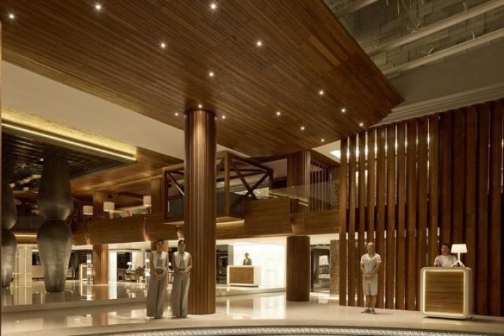 Double-Six Luxury Hotel Seminyak lobby. Gay-friendly hotel with wood design, staff at reception. Upscale, modern interior. Bali travel.