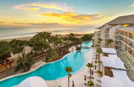 Double-Six Luxury Hotel Seminyak pool view. Gay-friendly hotel with beach access, palm trees, and ocean sunset. Ideal for gay travel.