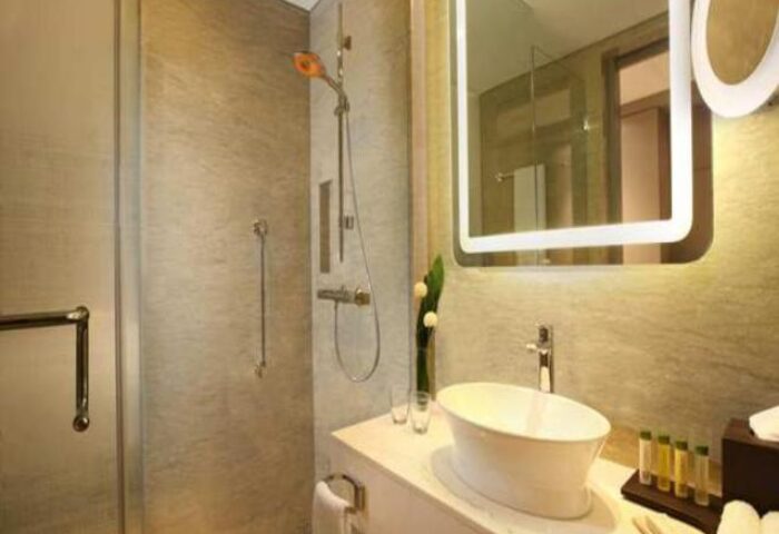 Bathroom at DoubleTree by Hilton Hotel Jakarta Diponegoro. Modern design with shower, sink, and illuminated mirror. Gay-friendly hotel in Jakarta.