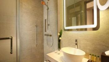 Bathroom at DoubleTree by Hilton Hotel Jakarta Diponegoro. Modern design with shower, sink, and illuminated mirror. Gay-friendly hotel in Jakarta.