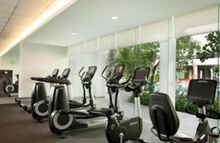 Gym at DoubleTree by Hilton Hotel Jakarta Diponegoro, a gay-friendly hotel. Treadmills and exercise bikes face windows overlooking the pool.
