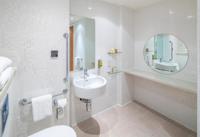 DoubleTree by Hilton Hotel Manchester-Piccadilly bathroom. Accessible features, round mirror, white tiles. Gay-friendly hotel for gay men travel.