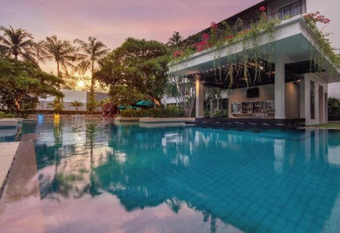 Pool at DoubleTree by Hilton Phuket Banthai Resort, a gay-friendly hotel. Swim-up bar, palm trees, and sunset. Perfect for gay travel.
