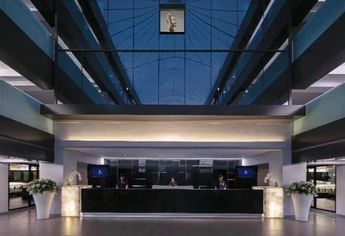 DoubleTree by Hilton Phuket Banthai Resort lobby. Gay-friendly hotel's modern reception area with staff, flowers, and glass ceiling.