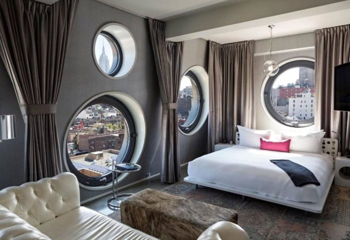 Dream Downtown Hotel room. Gay-friendly hotel with round windows, city views, bed, and couch. Great for gay men's travel.