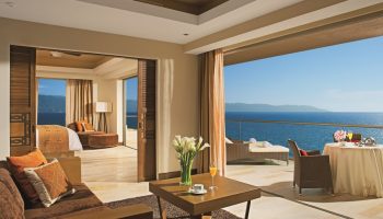 Dreams Vallarta Bay Resort & Spa All Inclusive suite. Gay-friendly hotel room with balcony, ocean view, bed, and living area.