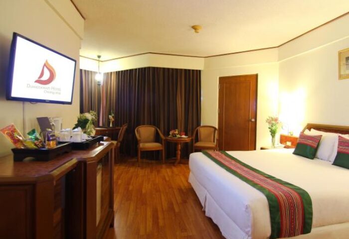 Duangtawan Hotel Chiang Mai room interior. Gay-friendly travel destination with TV, bed, and chairs. Thailand hotel for gay men's vacation.