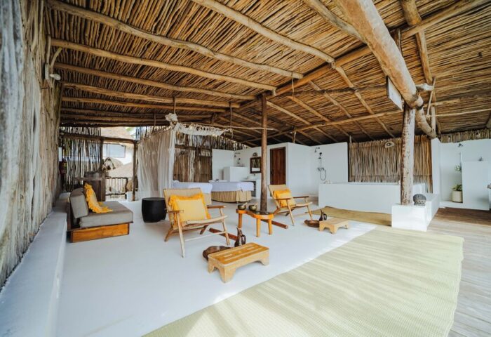Dune Boutique Hotel's gay-friendly suite in the party zone. Open-air design with thatched roof, lounge chairs, and spa area. Relaxing Tulum vibe.