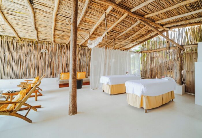 Dune Boutique Hotel, a gay-friendly party zone hotel. Spa room with massage tables, wood walls, and a thatched roof. Relaxing space.