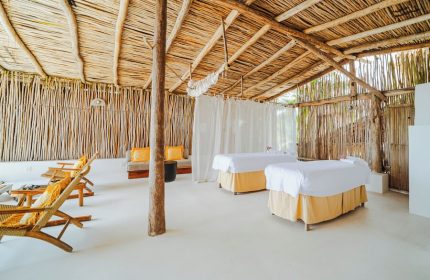 Dune Boutique Hotel, a gay-friendly party zone hotel. Spa room with massage tables, wood walls, and a thatched roof. Relaxing space.