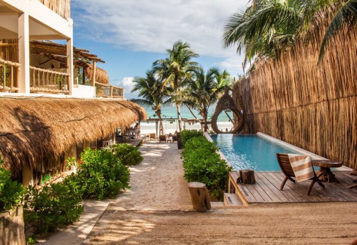 Dune Boutique Hotel, a gay-friendly hotel in the party zone. Pool view with beach access. Tropical, thatched roof, and palm trees.
