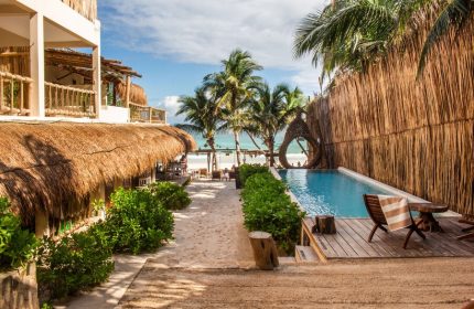 Dune Boutique Hotel, a gay-friendly hotel in the party zone. Pool view with beach access. Tropical, thatched roof, and palm trees.