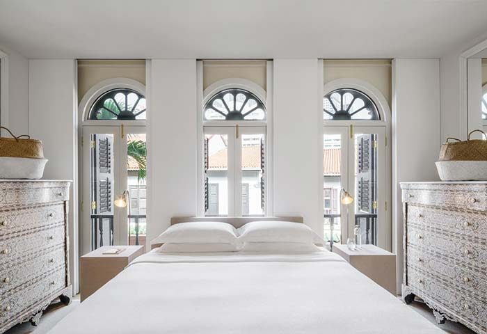 Bedroom at Duxton Reserve Singapore, Autograph Collection. Gay-friendly hotel with white linens, arched windows, and stylish decor. Singapore travel.