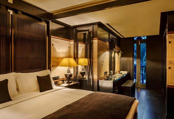 Bedroom at Duxton Reserve Singapore Autograph Collection, a gay-friendly hotel. Dark wood panels, lamps, and a view to the outside.