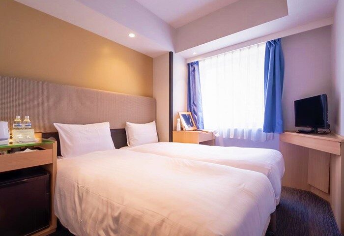 E-Hotel Higashi Shinjuku Tokyo room. Twin beds, desk, and TV in a gay-friendly hotel. Modern decor, comfortable for travelers.