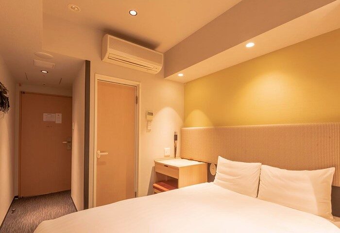 E-Hotel Higashi Shinjuku Tokyo gay-friendly room. Clean, modern interior with double bed, bedside table, and air conditioning. Comfortable stay.