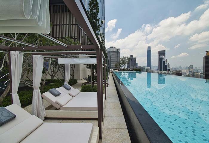 EQ Kuala Lumpur gay-friendly hotel's rooftop infinity pool. Daybeds under a canopy offer city views. Ideal for gay men's travel.