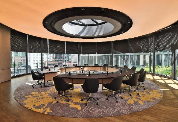 EQ Kuala Lumpur's gay-friendly hotel boardroom. Round table, black chairs, floor-to-ceiling windows, and a circular patterned rug.